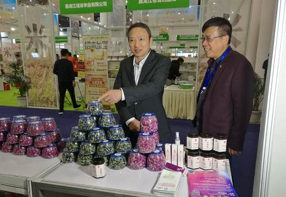 省委臺辦主任周敏謙(左)在四川雙龍農牧開發有限公司展臺與臺商林云飛(右)親切交流