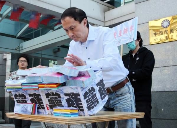 國民黨主席候選人李新提議“黨產歸零,黨員分配”,在記者會上推倒象征黨產的墻